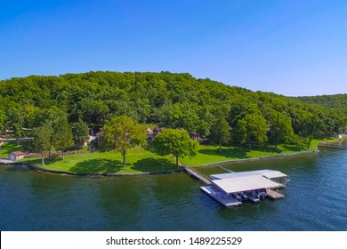 Lakeside Home And Dock At Lake Of The Ozarks Missouri On A Summer Sunny Day With Green Trees, Blue Water, And Blue Sky.