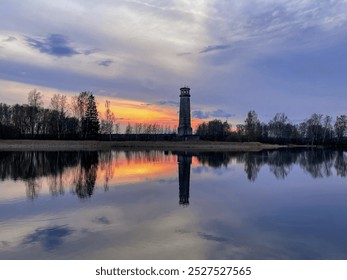 A lakeside lighthouse is reflected in the water at sunset. - Powered by Shutterstock