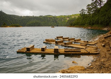 Lakeside Serenity: Wooden Pier on a Chiapas Lake, Azure Waters, Lush Trees, Earthy Ground, Distant Boats, Overcast Day. Montebello's Lake. - Powered by Shutterstock