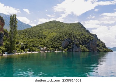 Lakeside town Trpejca nestled amidst lush green mountains of National Park Galicica, North Macedonia. Serene scene along shoreline of Lake Ohrid. Boat trip summer vacation. Balkan travel destination - Powered by Shutterstock