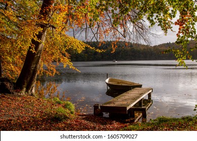 Lakeside View With Jetty And Row Boat In Beautiful Fall Landscape