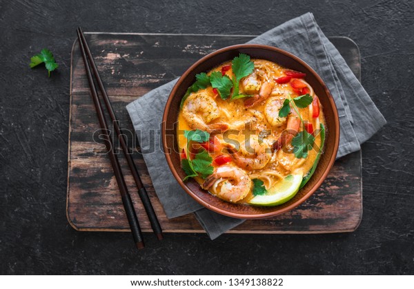 Laksa Shrimp Soup.\
Prawn noodle laksa soup on black background, top view, copy space.\
Asian Malaysian food.