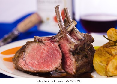 lamb chop meal with potato and carrot. Red wine with a glass in the background. Very shallow depth of field.