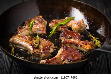 Lamb chops frying in a rustic metal pan with rosemary and mixed pepper - Shutterstock ID 1190747692