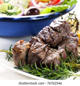 Lamb Kebabs On Rosemary Skewers, With Greek Salad Behind.