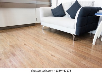 Laminate Wood Floor Background. Oak Wood Surface On The Floor. With White Sofa. Living Room Install Wood Laminate Floor.