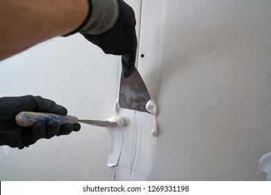 laminated plasterboard plastering join detail spatula and hand - Shutterstock ID 1269331198