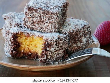 Lamington cake, squares of sponge cake coated in chocolate sauce and rolled in desiccated coconut on plate