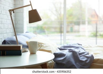 Lamp, books and cup on a side table