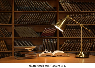 Lamp, books and glasses on wooden table in library - Powered by Shutterstock