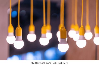 A lot of lamp bulbs hanging on yellow wires from ceiling. Bright idea bulbs concept. - Powered by Shutterstock