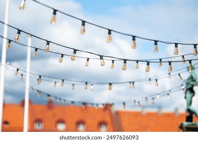 Lamp bulbs on wires crossing above a street - Powered by Shutterstock