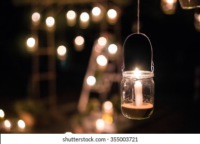 The lamp made of a jar with a candle  is  hanging  on a tree at night. Wedding night decor. Night ceremony