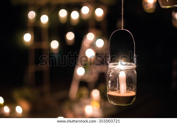 The lamp made of a\
jar with a candle  is  hanging  on a tree at night. Wedding night\
decor. Night ceremony
