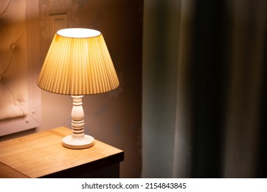 Lamp. Night light by the bedside table with warm light. Intimate setting. Lamp for reading a book on the bed. Bedside table with night light