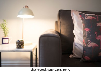 Lamp On A Marble Bedside Table Next To A Brown Comfortable Lounge With Cushions Pillows