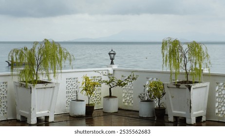 Lamp on Railing with Potted Trees and Sea Horizon Background - Powered by Shutterstock