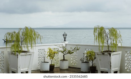 Lamp on Railing with Potted Trees and Sea Horizon Background - Powered by Shutterstock