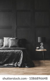 Lamp On Wooden Table Next To Bed In Modern Black Bedroom Interior With Molding On The Wall