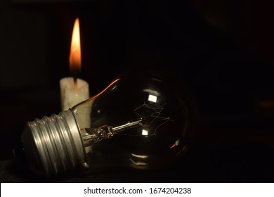 A Lamp And One Candle Blur Burning In The Dark Background. Power Outage. Blackout Begin.