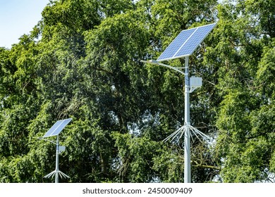 Lamp post with solar panel system on road with blue sky and trees. Autonomous street lighting using solar panels. Street lamp, on batteries from the sun. Alternative renewable energy systems.