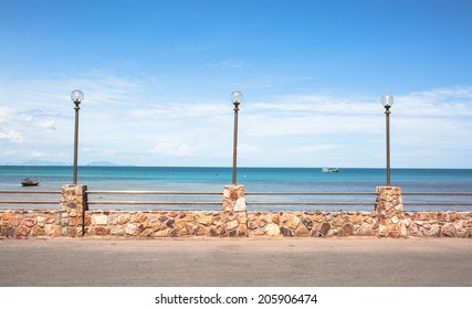 Lamp Post And Stone Fence On Road Beside Blue Sea