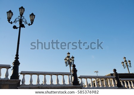 lamp posts on a pier with railing at sunny spring day with clear blue sky