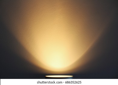 The lamp shines with warm light on the wall. Warm lighting.