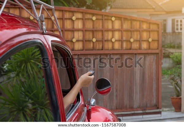 LAMPANG\
THAILAND - AUGUST 27 2018 :Woman in red Volkswagen car, hand using\
remote control to open or close the automatic gate while driving\
and leaving home.Safety and save time\
concept.