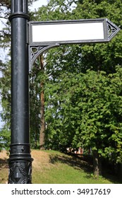 Lamppost with the arrow pointer against city park