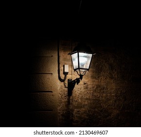 Lamppost illuminating a wall of an old house at night in Vic