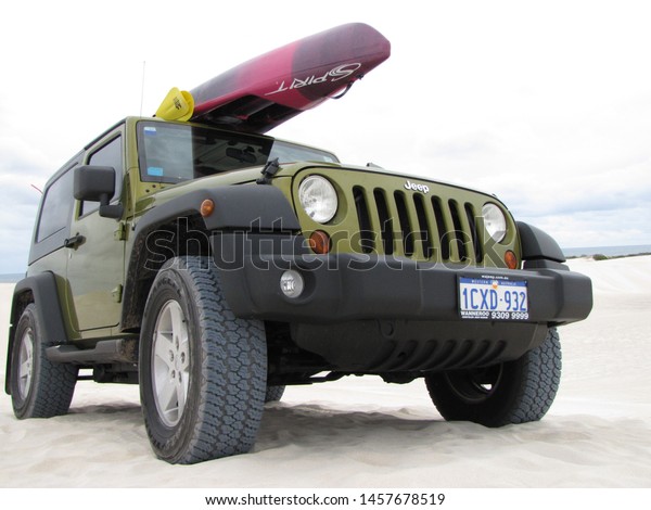 LANCELIN, WESTERN AUSTRALIA- FEBRUARY 6, 2010. Close-up\
of green Jeep sport Wrangler with pink and purple double kayak on\
the roof parked at the top of a sand dune in Lancelin, Western \
Australia. 