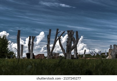 Land Art Installation Outdoors. Composition Of Trees Against The Background Of The Sky And Clouds.