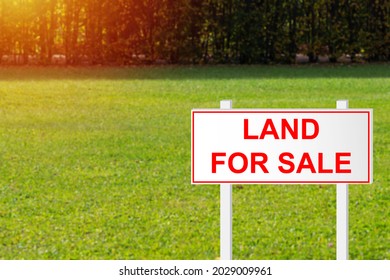 Land For Sale. Land For Sale Sign On Green Grass. Purchase Of Site Plot. Purchase Of Empty Land. Purchase Of Site For Construction Of House. Sign Advertising Ground On Clipped Grass Background