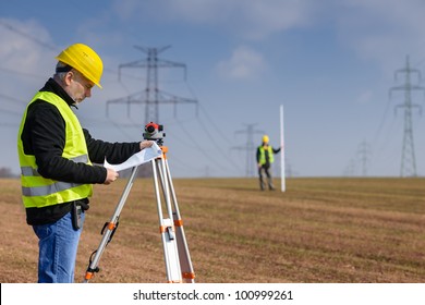 Land surveyors on construction site reading plans wear reflective clothing