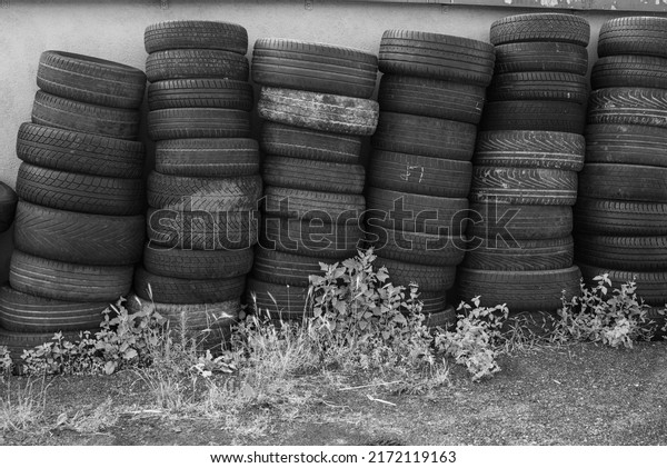 Landfill with old tires and tyres for recycling.\
Disposal of waste tires. Worn out wheels for recycling. Tyre dump\
burning plant. Regenerated tire rubber produced. stacks of used\
tires. black white