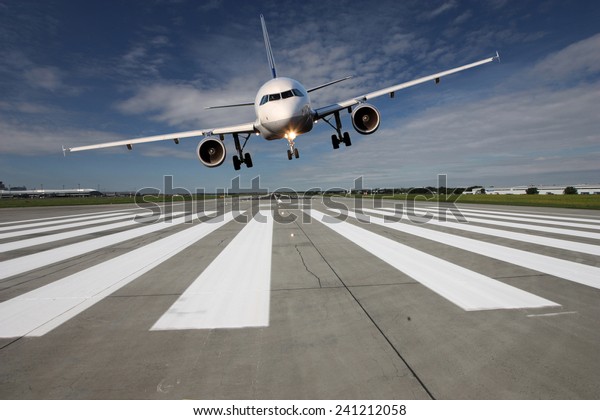 Landing aircraft low over the runway with stretched\
landing gear