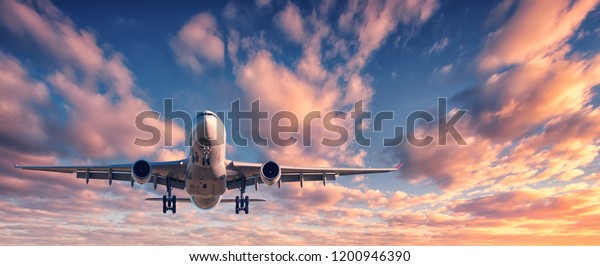 Landing airplane against colorful sky at sunset.\
Landscape with aircraft is flying in the blue sky with multicolored\
clouds. Travel background with passenger plane. Commercial\
airplane. Private jet