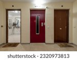 Landing of a house with an elevator with a red door and an open access door