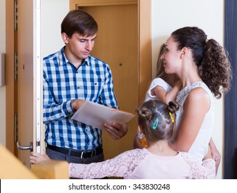 Landlord Standing Indoors And Asking Family Of Tenants For Money