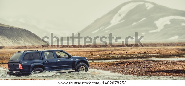 Landmannalaugar, Iceland - July 2, 2018: 4WD vehicle\
car travel off road in landscape of Landmannalaugar in highland of\
Iceland, Nordic, Europe. The place is famous for summer outdoor\
trekking way.