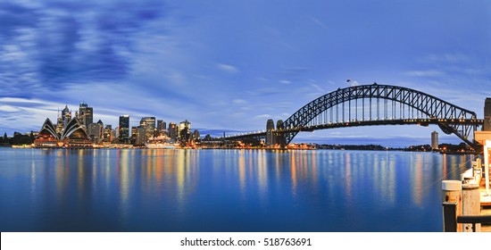 Landmarks of Sydney city CBD across Harbour with bridge, circular quay, passenger terminal and downtown skyscrapers to Kirribilli pier at blue cloudy sunrise. - Powered by Shutterstock