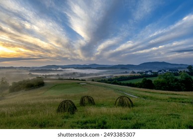 Landscape with backlit clouds and mists over the hills just after sunrise