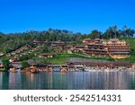 landscape of "Ban Rak Thai Village in Mae Hong Son province at dusk, showcasing a serene lakeside scene with floating lanterns and glowing reflections, surrounded by traditional buildings