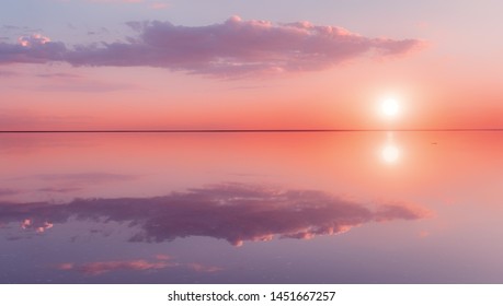 Landscape beautiful lilac sunset red sky solt lake saline Elton Baskunchak. The sun sets behind the horizon. The clouds are like the hands of a man holding the sun. Zen harmony, serenity, tranquility