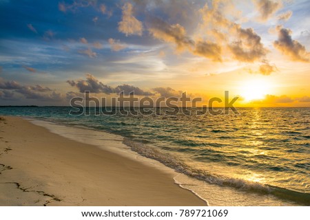 Landscape of beautiful sunset in Maldives island sandy beach with colorful sky and dramatic  clouds over wavy sea