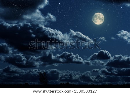 landscape with a big moon and dramatic sky with clouds