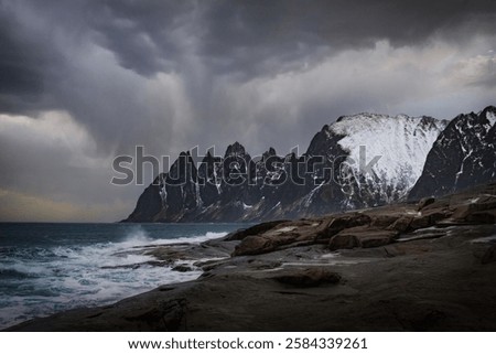 Landscape with breaking waves in front of the Devils Teeth on the Island of Senja in Northern Norway