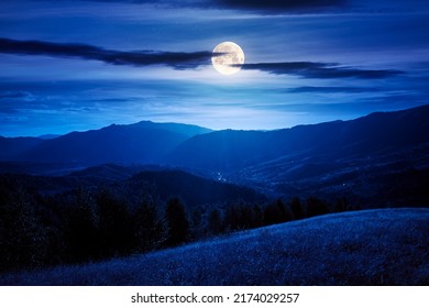 landscape of carpathian countryside at night. early autumn season in mountains in full moon light. trees on the grassy hills rolling in to the distant valley