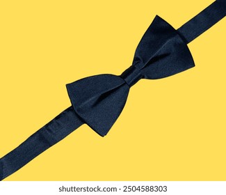 Landscape close, top-view of an elegant men’s formal black silk bow tie neck fashion accessory, displayed against a vibrant, bright, solid yellow background, as if it were gift wrapping for a present. - Powered by Shutterstock